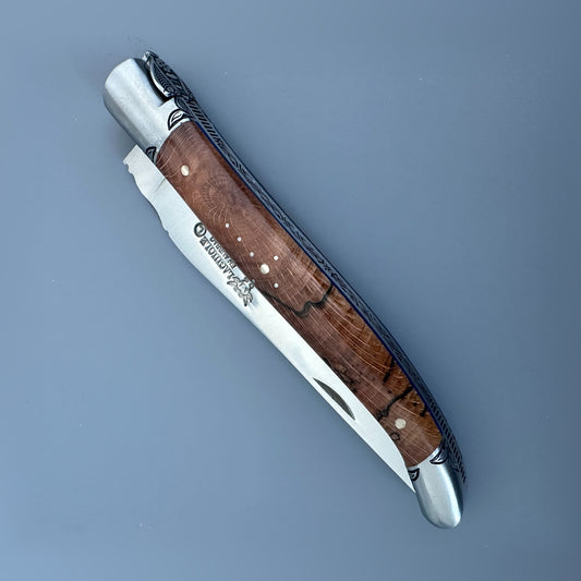Closed front view of a Laguiole en Aubrac Belle Piece knife with wood handle, blue spacer and decorative pinwork