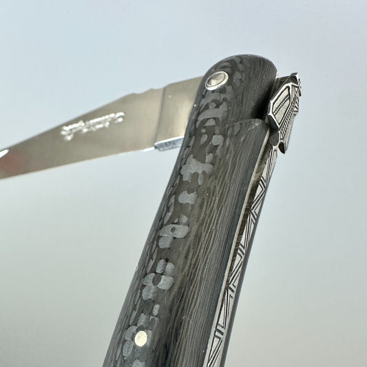 Close-up of the carbon handle and partly open blade on a Laguiole en Aubrac Belle Piece Carbon folding knife.