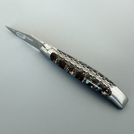 Angled view of a Laguiole en Aubrac double-plated knife with brown mammoth molar handle and decorated file work