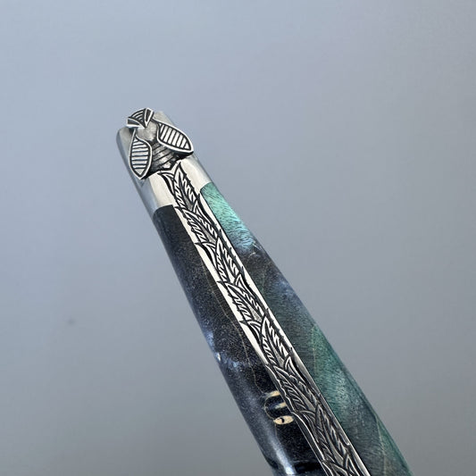 Macro shot of the Laguiole en Aubrac knife's bolster and handle spine, showing detailed bee carving and fern-leaf engraving