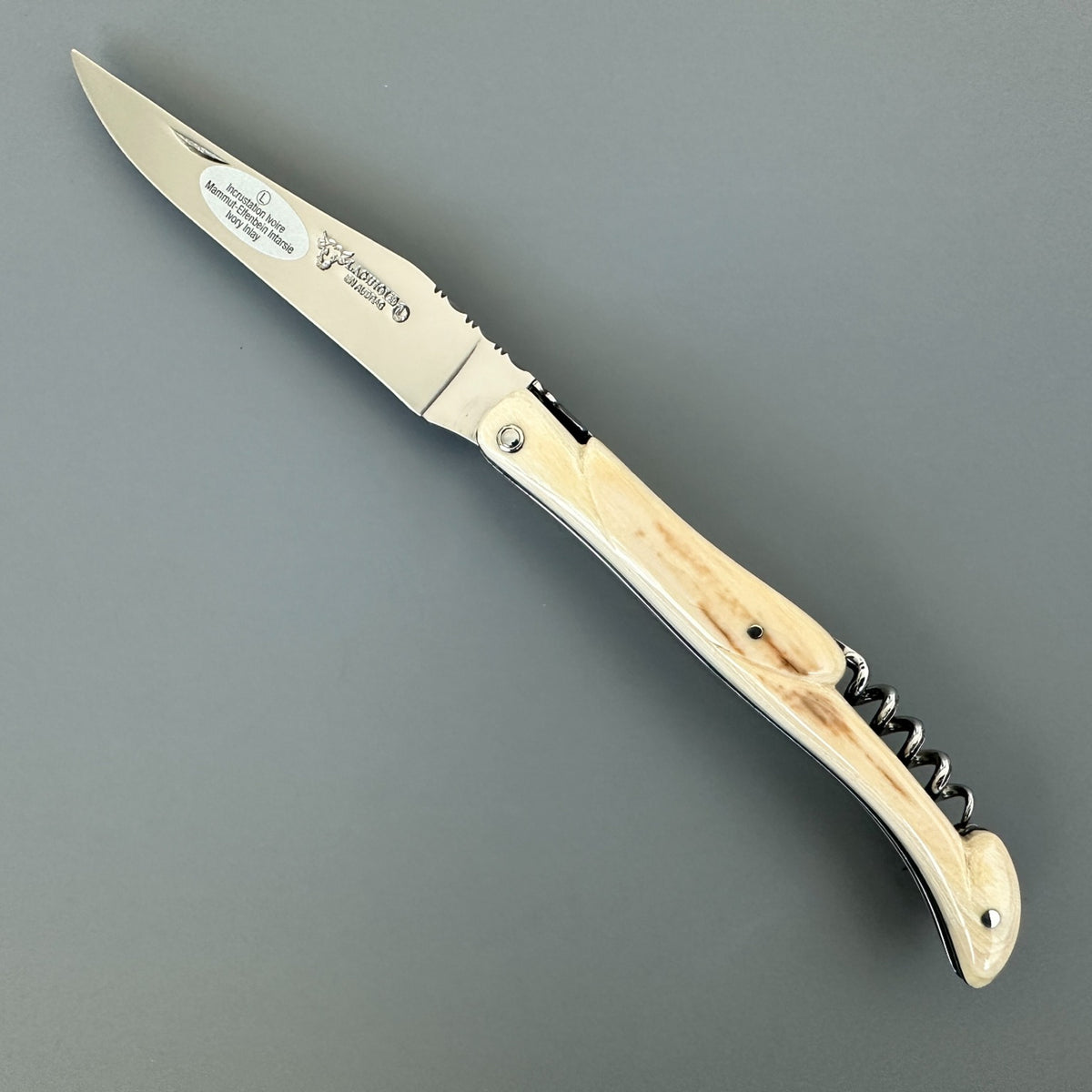 Fully open Laguiole en Aubrac folding knife showing its blade logo, pale patterned handle, and folded corkscrew.