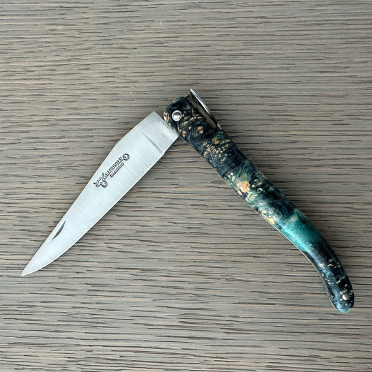 Folding knife with a decorative handle on a wooden surface