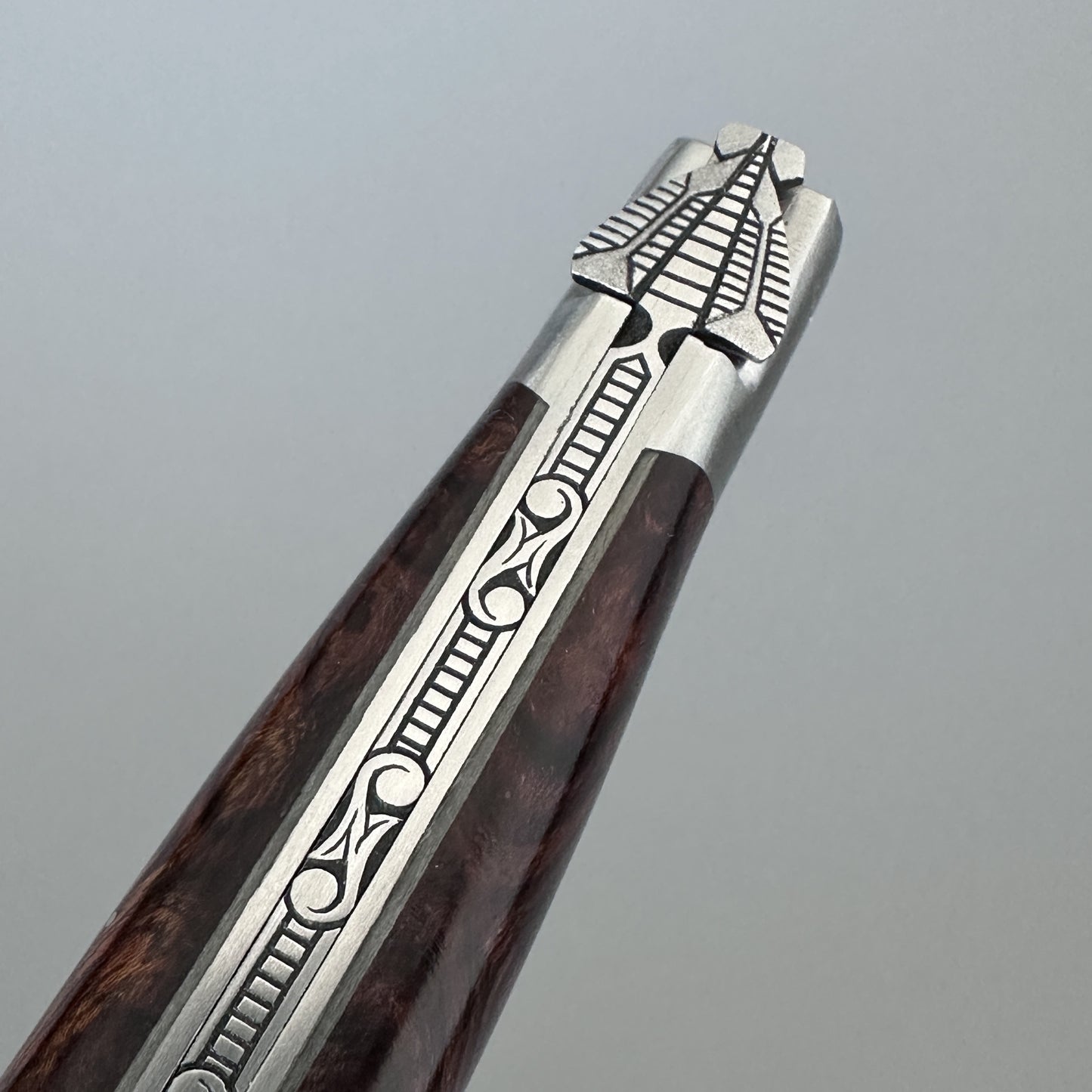 Macro close-up of the Laguiole en Aubrac Belle Double knife's bolster and spine, showing the engraved nickel silver Bee and decorative filework against the Ironwood handle.