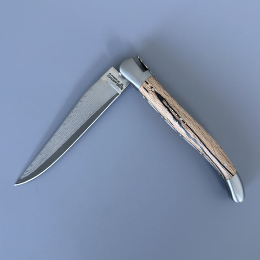 Reverse side of the Laguiole Double Plate Damascus knife, open, showing the Aubrac wood grain and Damascus blade.