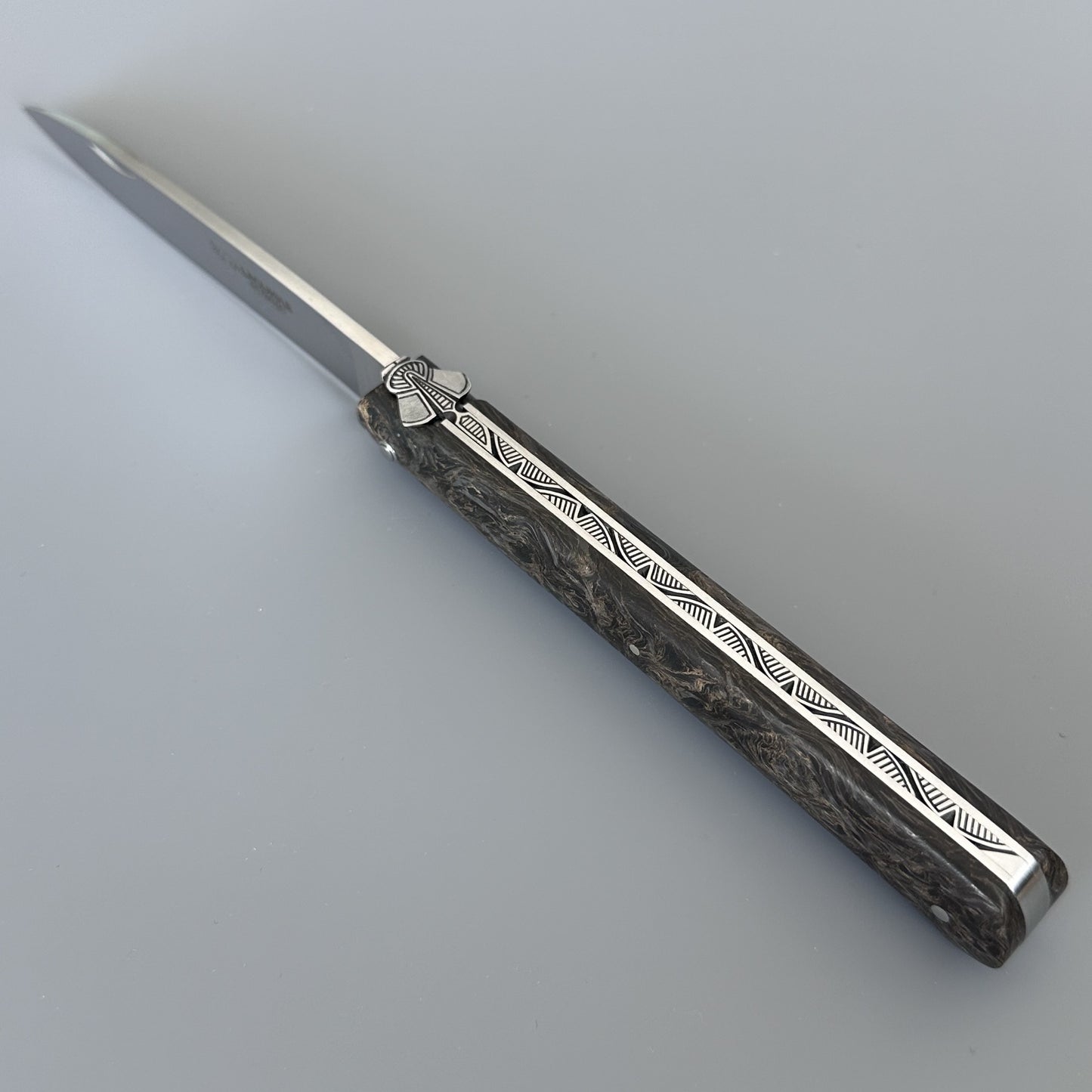 Close-up of the Laguiole Droit's fly and hand-engraved bee motif on the handle, showing the corbin beak tail detail