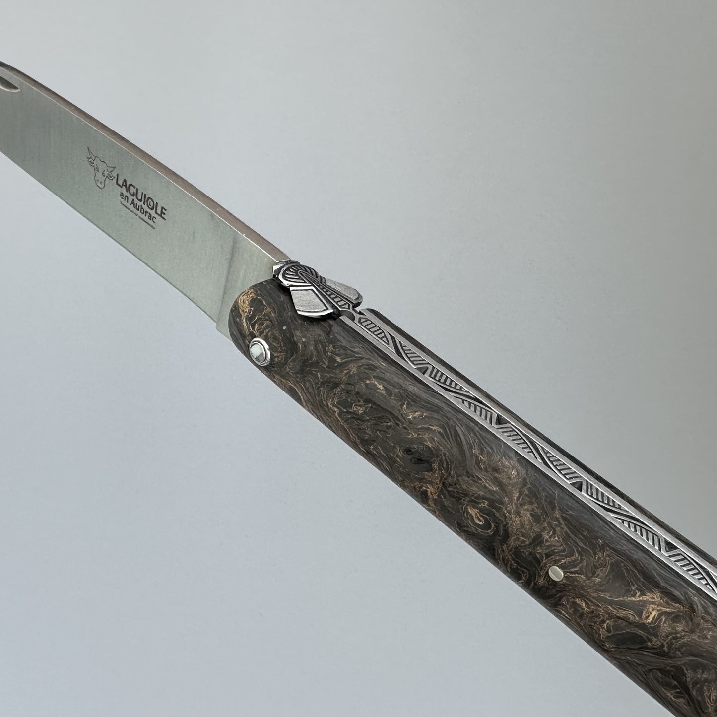 Macro shot of the Laguiole Droit's fly, engraved bee, and hand-carved leaf detailing along the spring