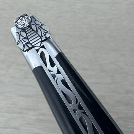 Macro shot of the hand-carved bee and silver filigree spring detailing on a Laguiole en Aubrac ebony-handled knife