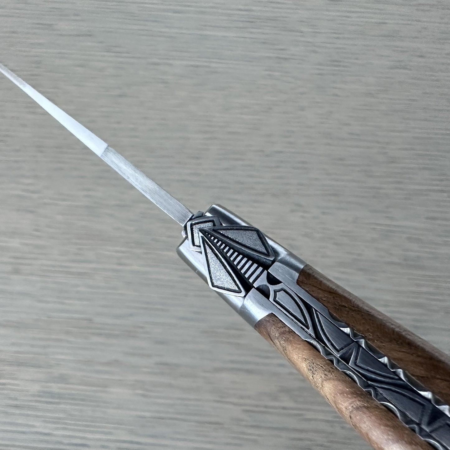 Macro shot of the special hand-carved bee and geometric silver filigree at the bolster of a Laguiole en Aubrac teak-handled knife