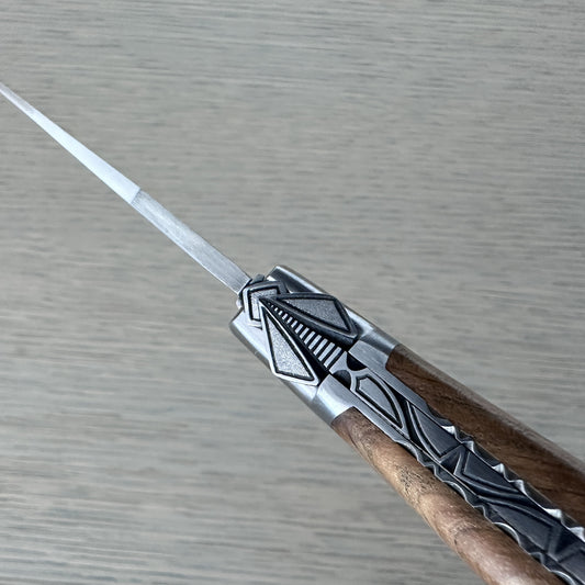 Macro shot of the special hand-carved bee and geometric silver filigree at the bolster of a Laguiole en Aubrac teak-handled knife