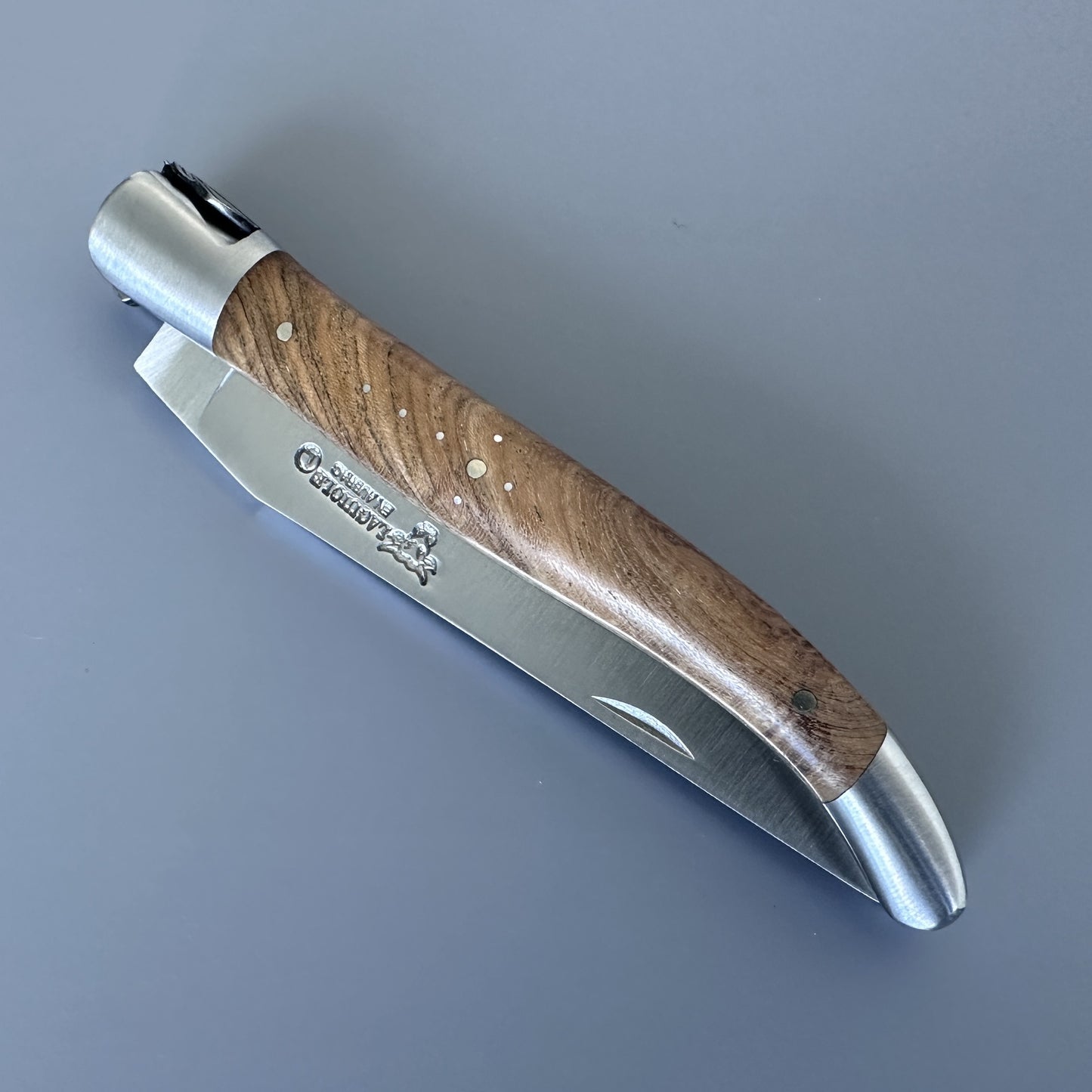 Laguiole en Aubrac knife closed, showing the teak handle grain and blade etched with the Laguiole bull logo