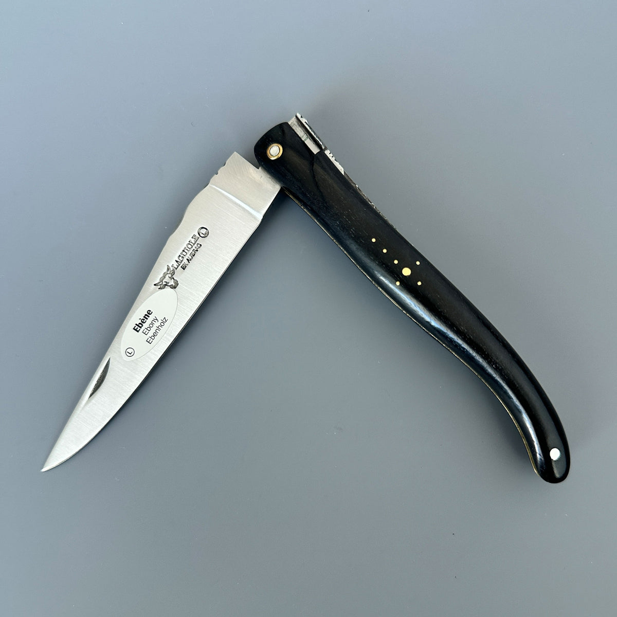 Laguiole en Aubrac Ebony & Brass Partially Folding Knife – Open Blade on Grey Background