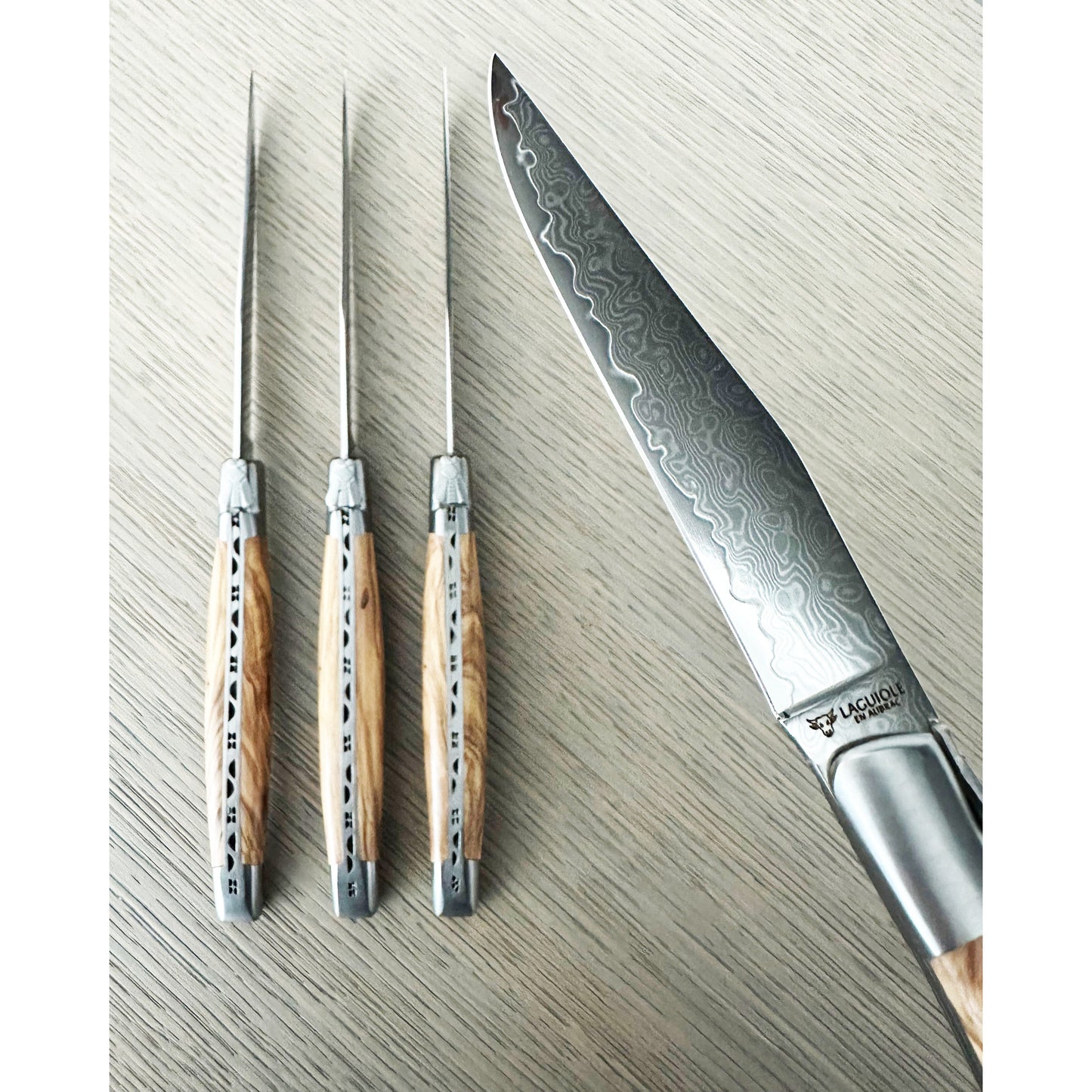 Set of four steak knives with olive wood handles on table background