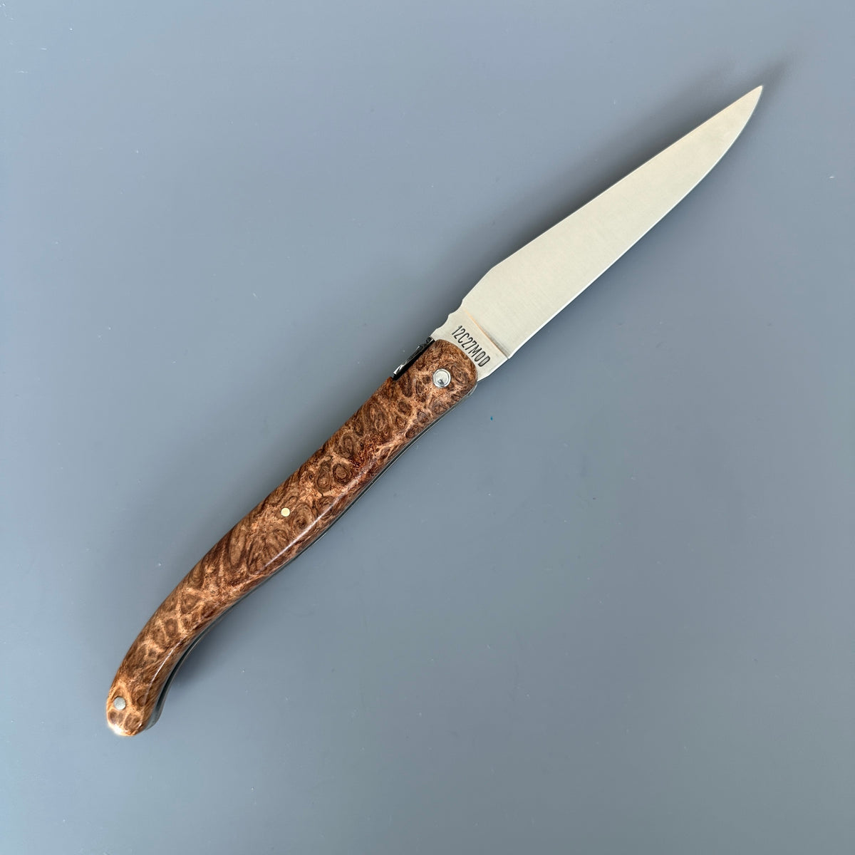 Reverse side of a fully open Laguiole en Aubrac folding knife with Amboyna burl wood handle