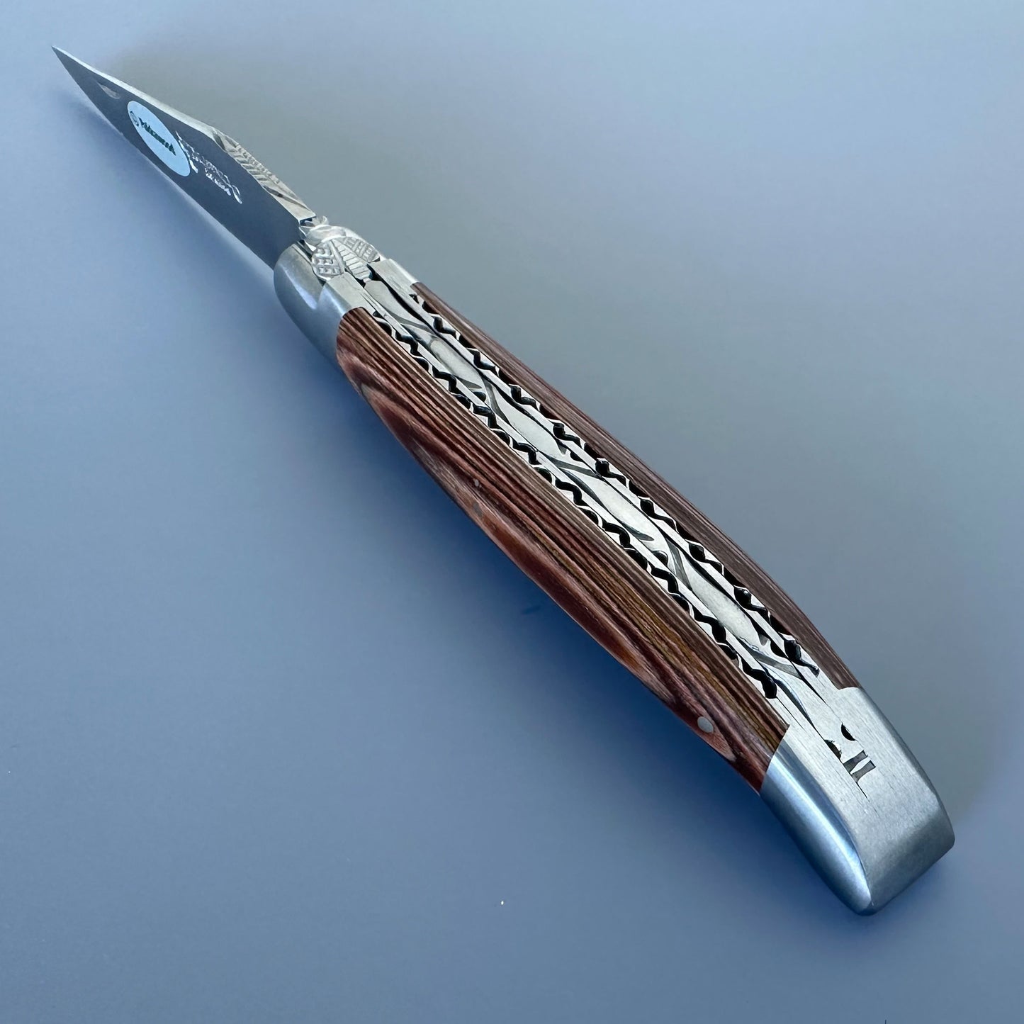 Close-up of the double-plated spine on a Laguiole en Aubrac knife, showing hand-carved caramel Pakka handle scales