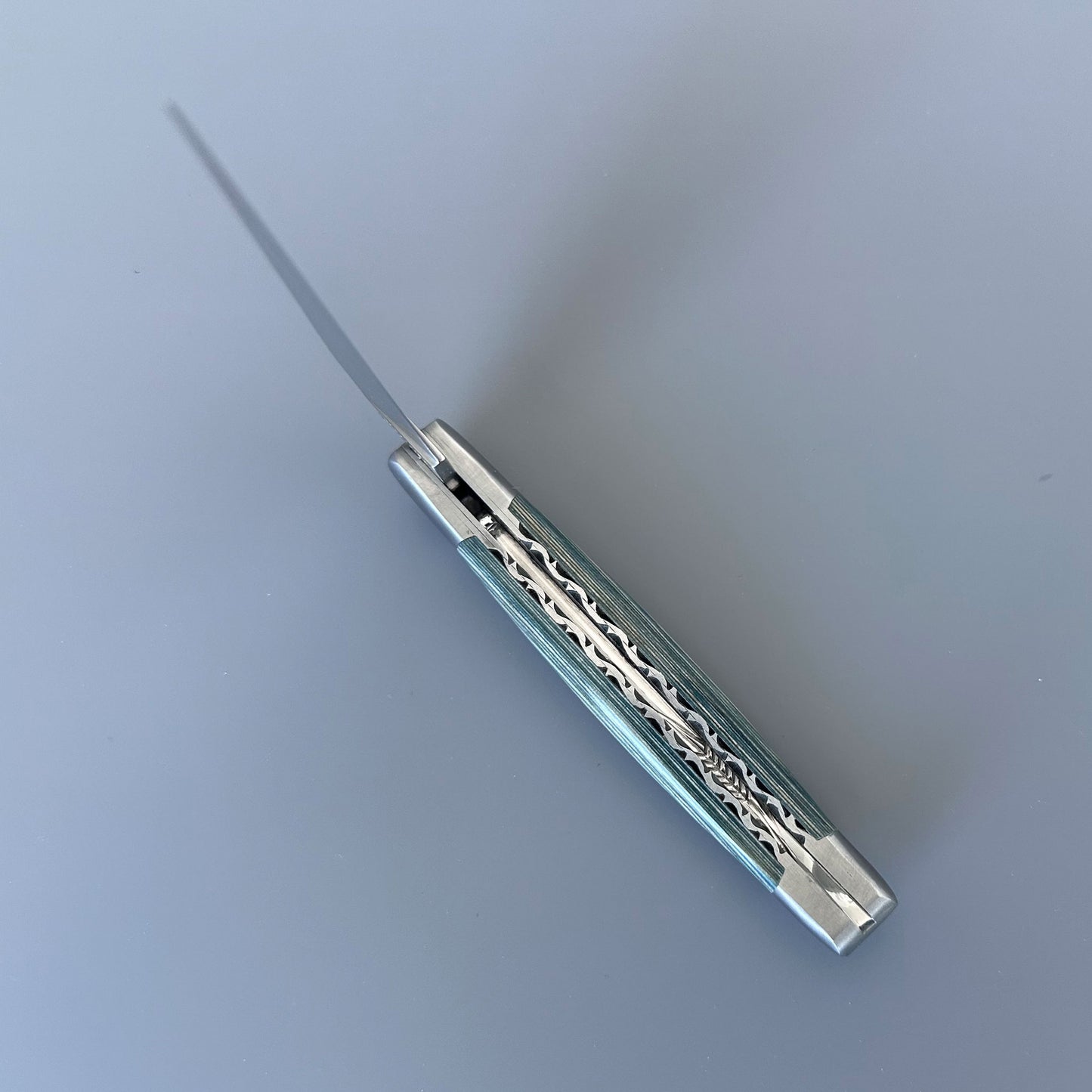 Close-up of the double-plated spine on a Laguiole en Aubrac knife, showing hand-carved blue Pakka handle scales