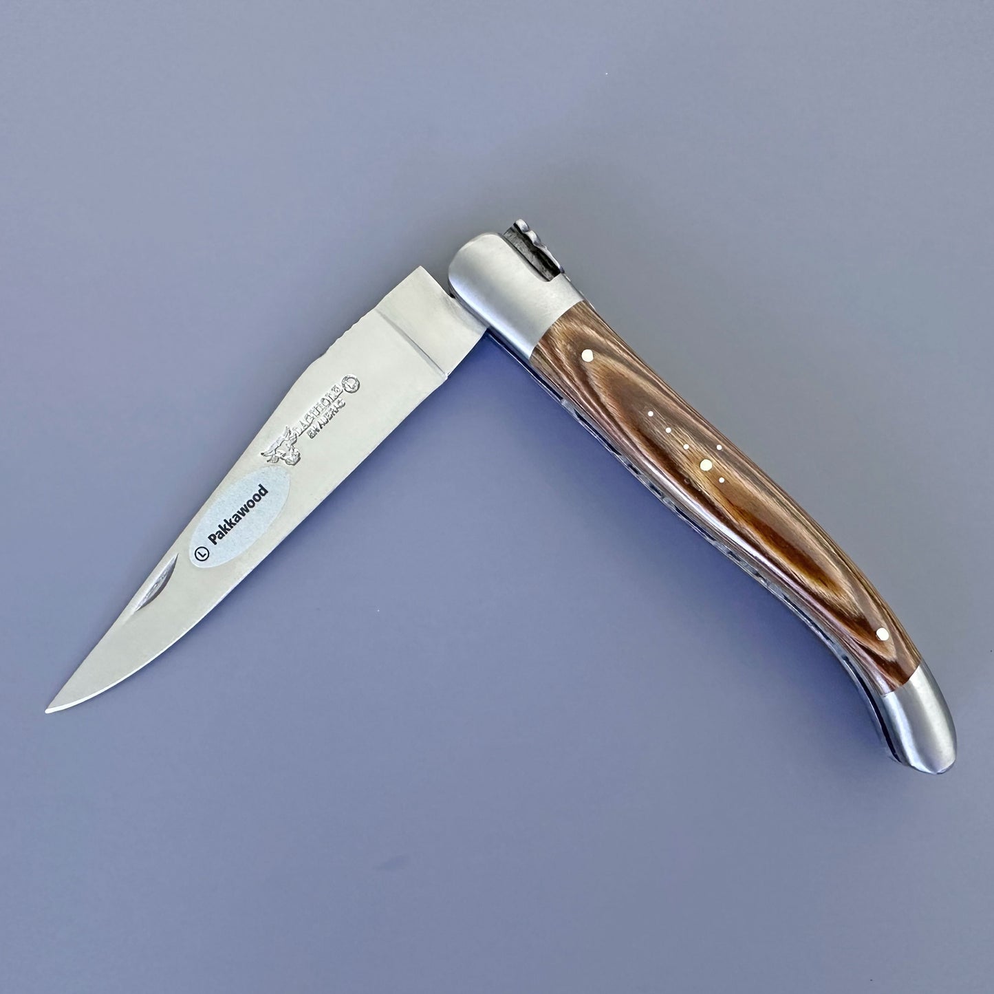 Laguiole en Aubrac folding knife with caramel Pakka wood handle and forged bee spring, shown open on a gray background