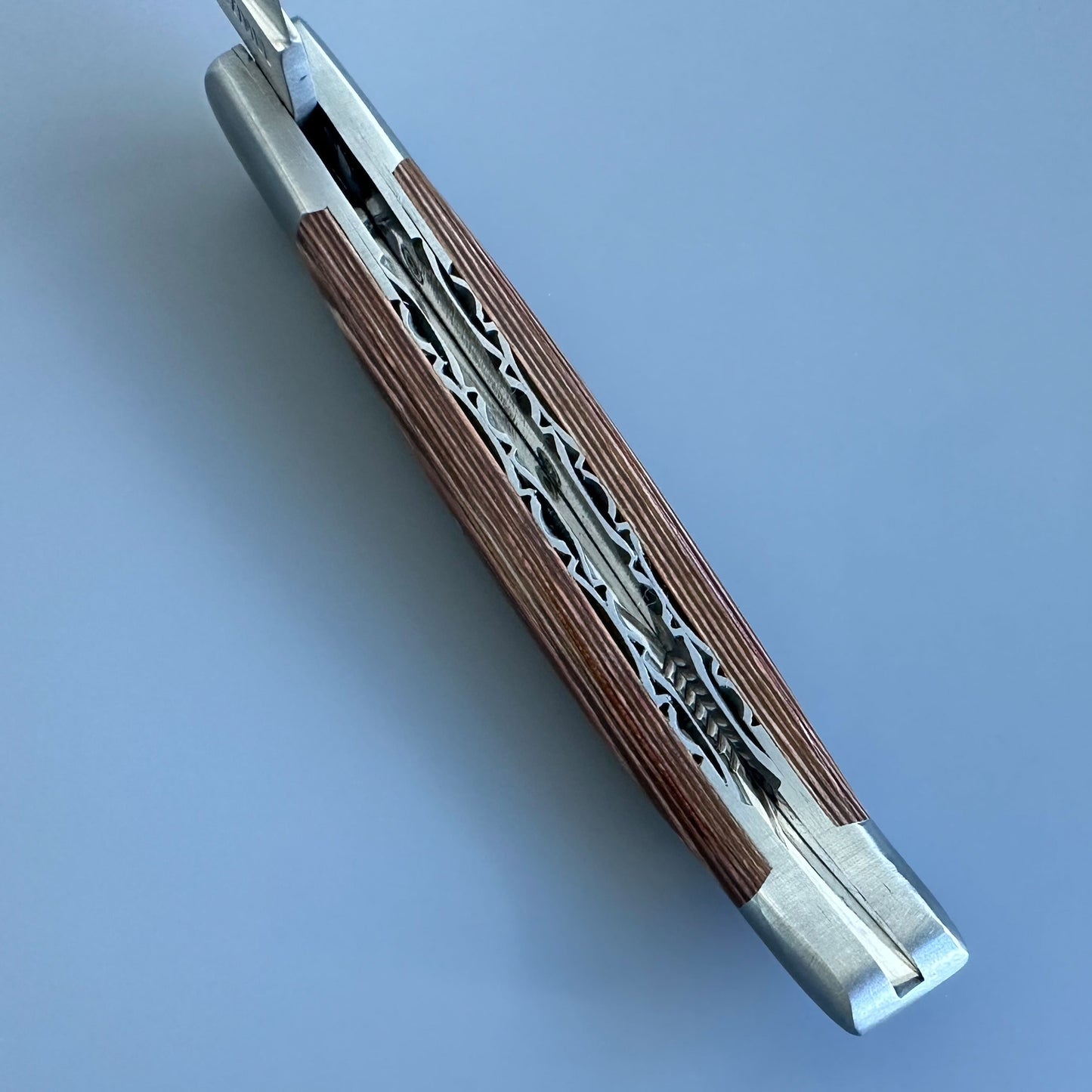 Close-up of the double-plated spine on a Laguiole en Aubrac knife, showing hand-carved caramel Pakka handle scales
