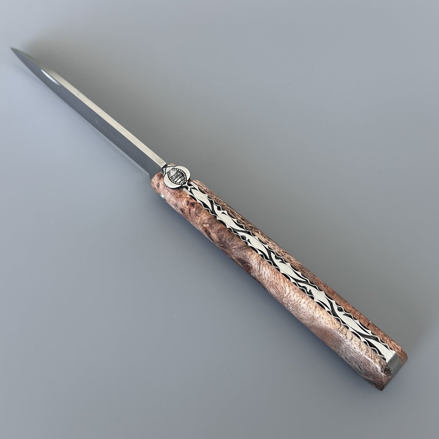 A folding pocket knife showing spine and textured handle, shown on a neutral gray background.