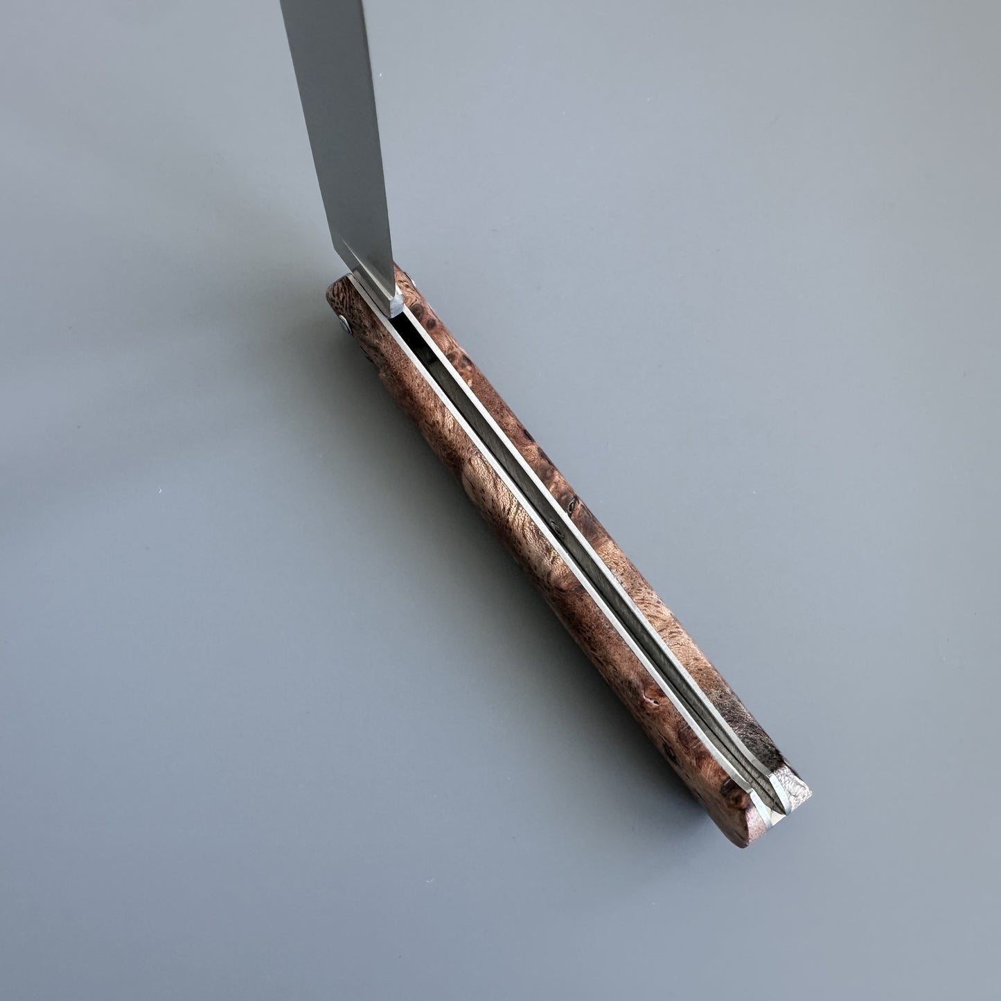 A folding pocket knife with a marbled brown and beige handle, shown partially open with a silver metal blade against a solid gray background.