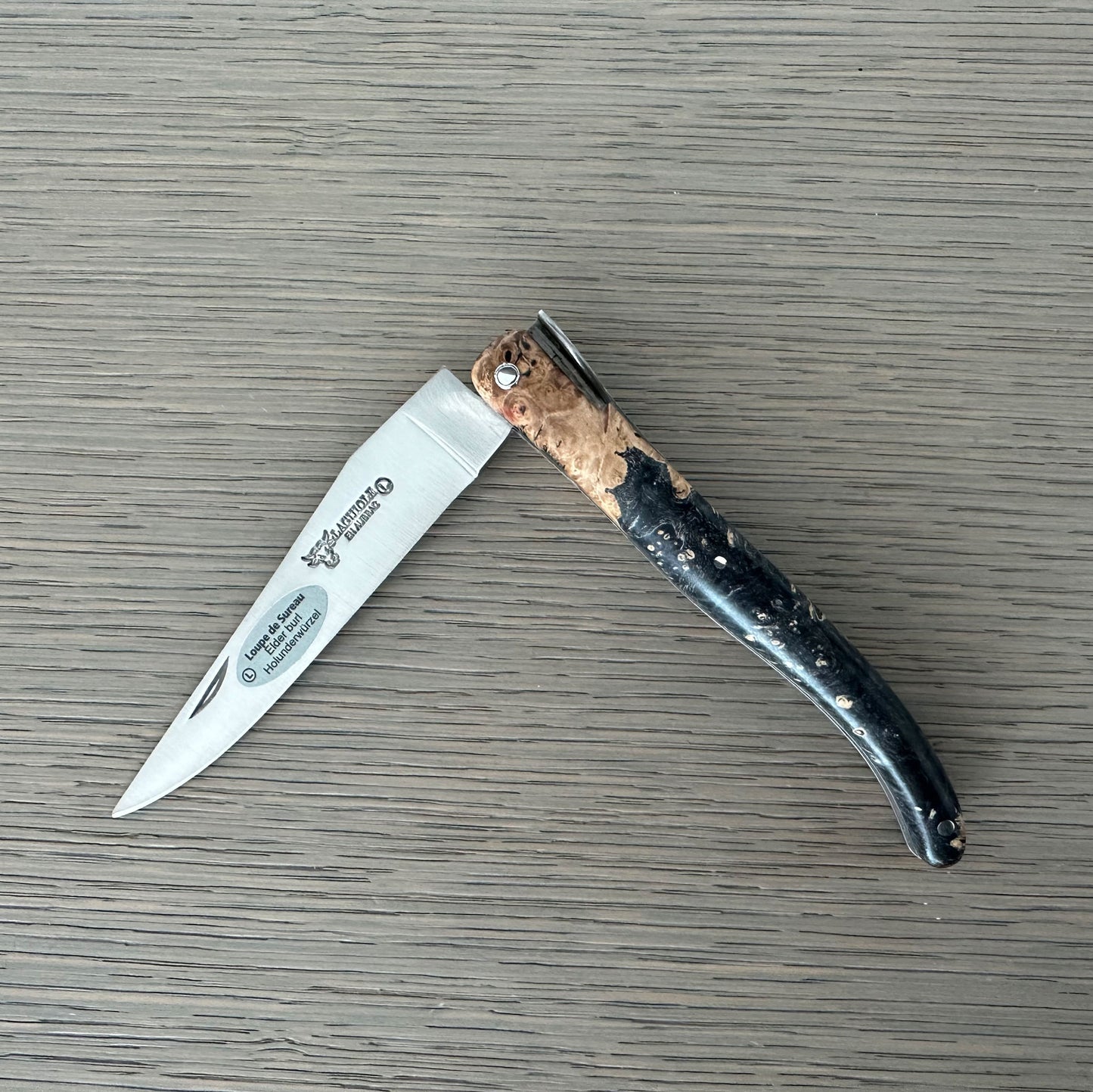 Folding knife with a decorative handle on a wooden surface