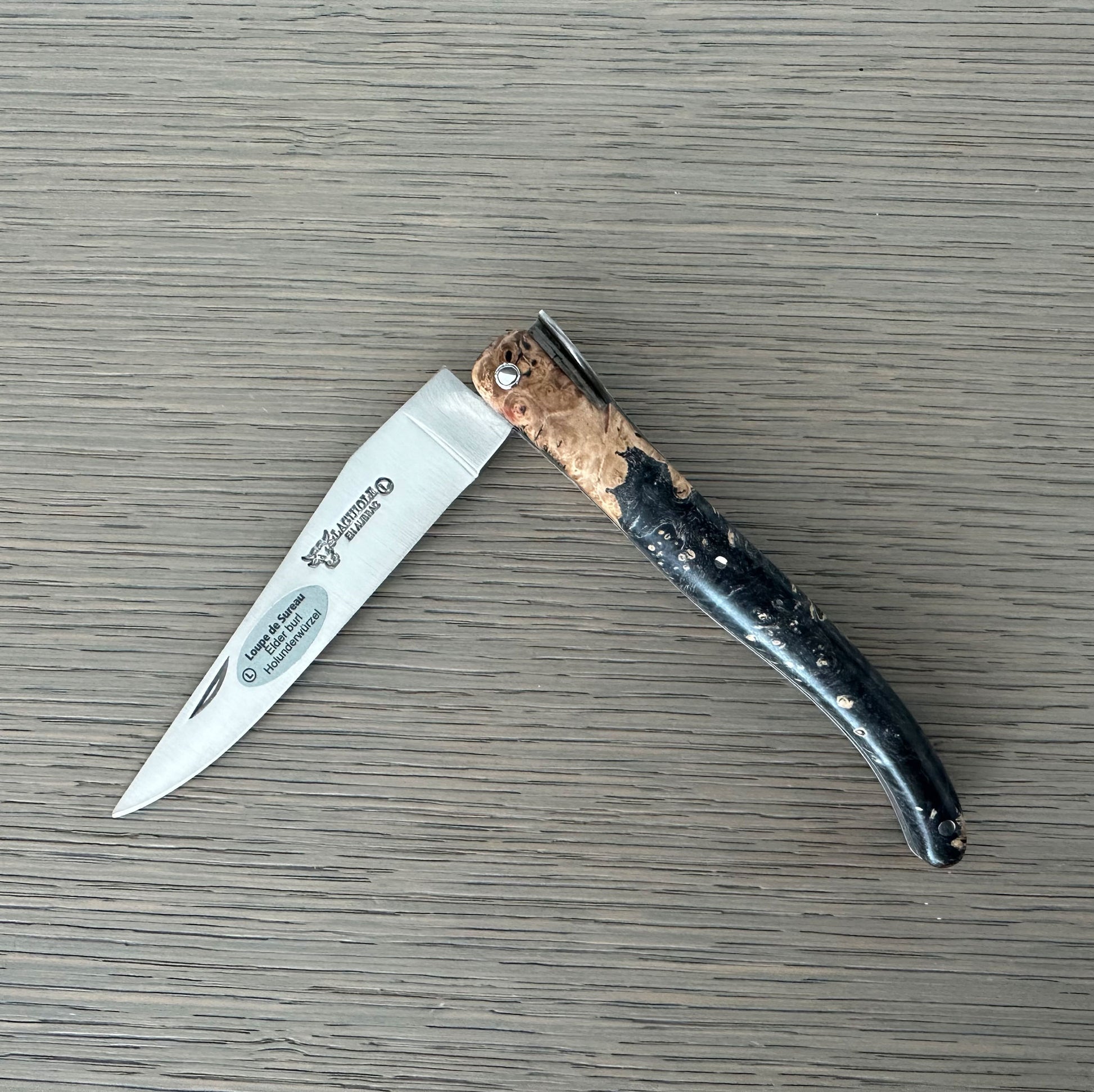 Folding knife with a decorative handle on a wooden surface