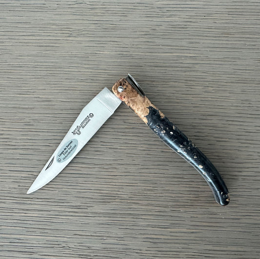 Folding knife with a decorative handle on a wooden surface