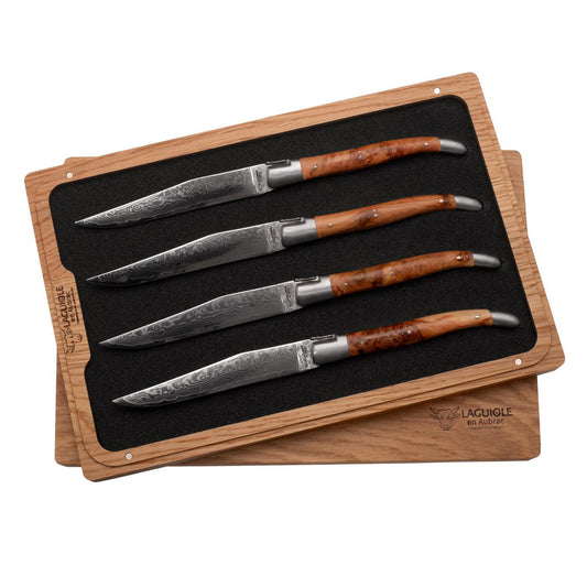 Set of four steak knives with wooden handles on a branded wooden block.