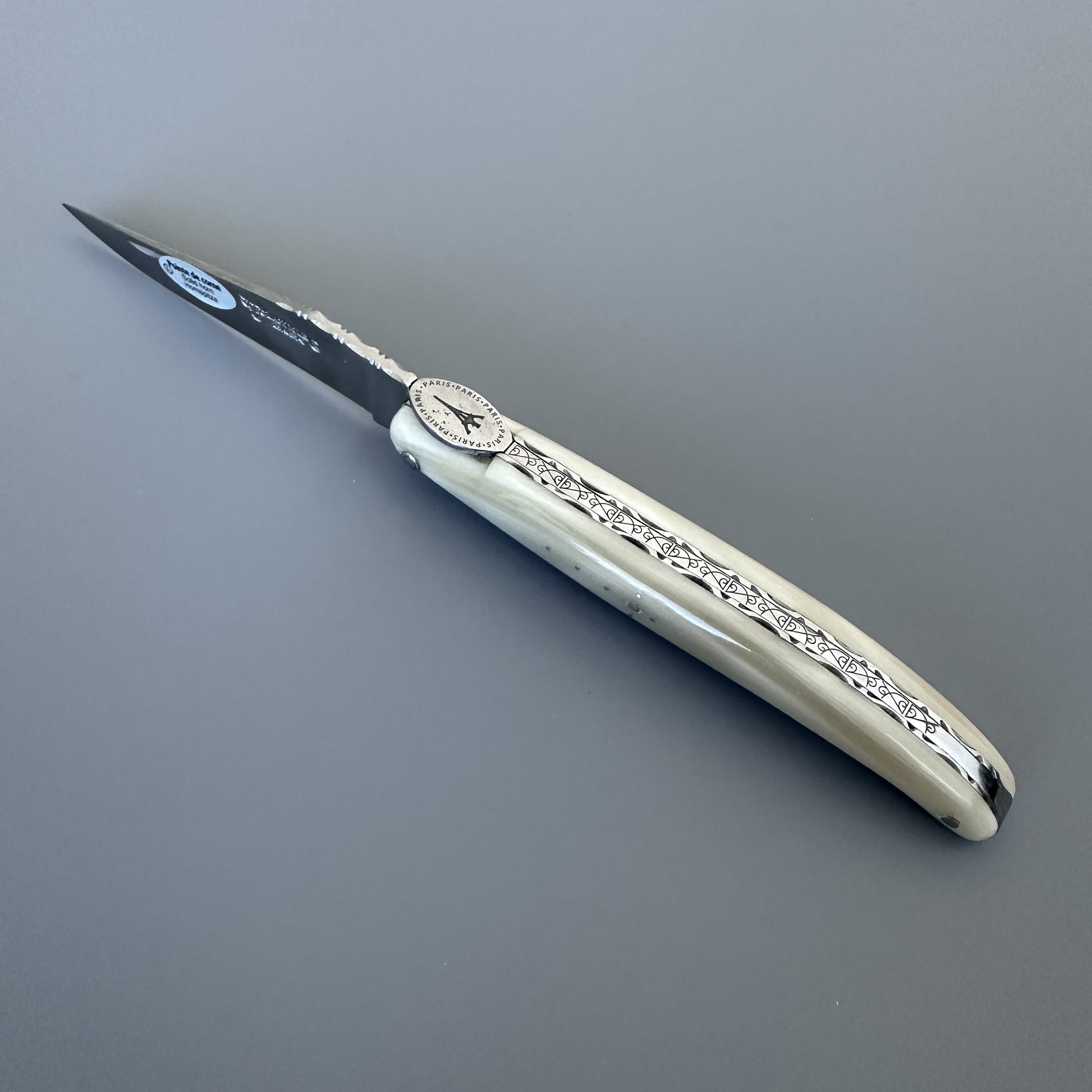 A folding pocket knife with a cream-colored bone handle and a silver-colored steel blade, shown closed on a neutral gray background.