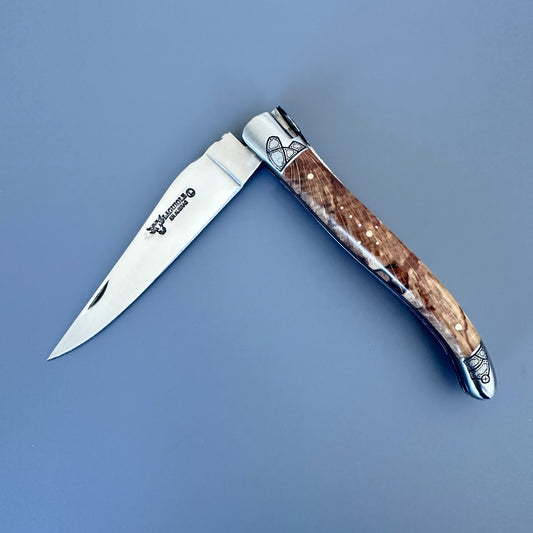 Angled open Laguiole en Aubrac Belle knife with Aubrac wood handle and guilloché bolsters