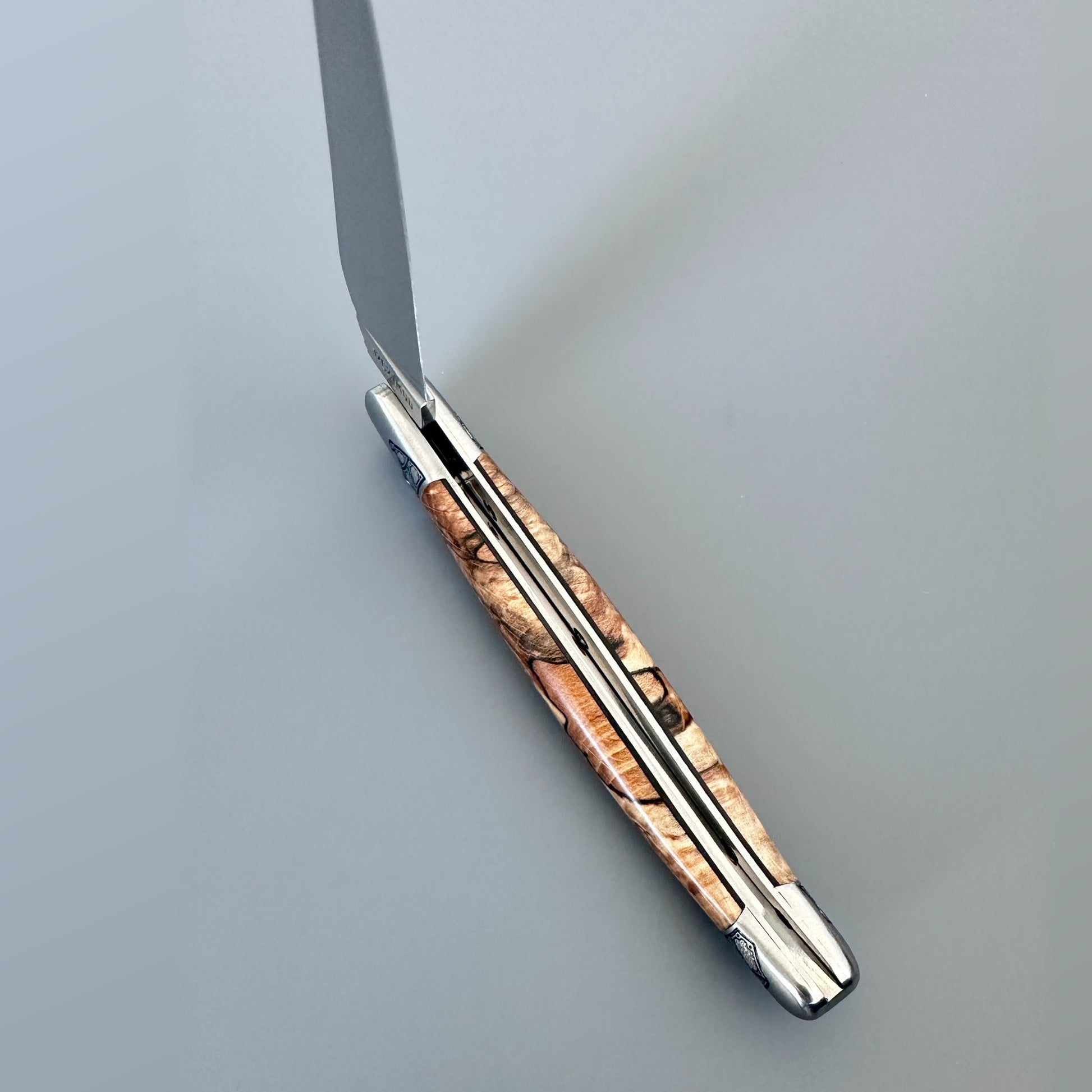 Spine view of an open Laguiole en Aubrac Belle knife showing Aubrac wood and black inlay