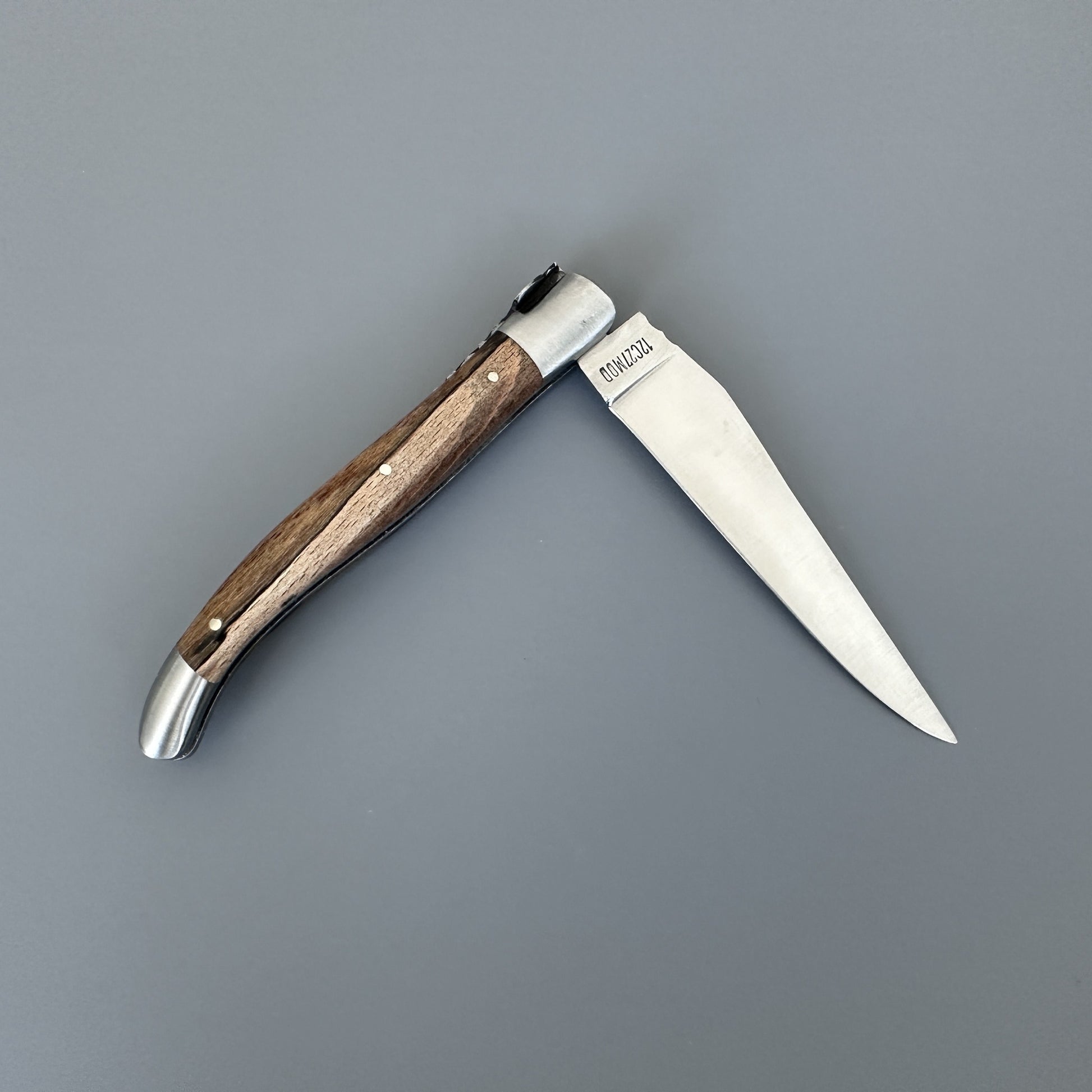 Alternate angle of the closed Belle knife showing the Aubrac wood scales and blade edge