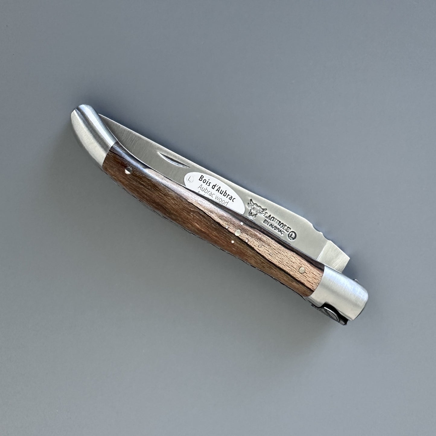 Closed Belle knife with Aubrac wood handle, showing the "Bois d'Aubrac" label and blade maker's mark