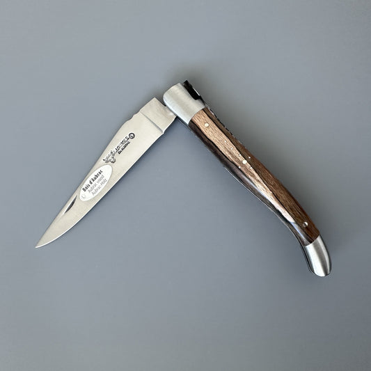 Closed Laguiole en Aubrac Belle knife with Aubrac wood grain handle and brand stamp on the blade