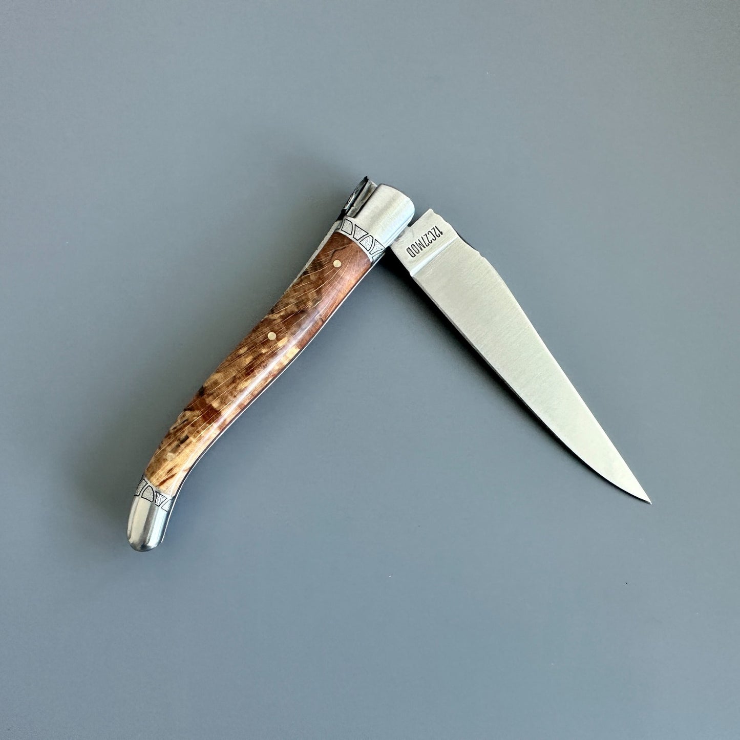 Reverse view of an open Laguiole en Aubrac Belle knife with Aubrac wood handle and red inlay