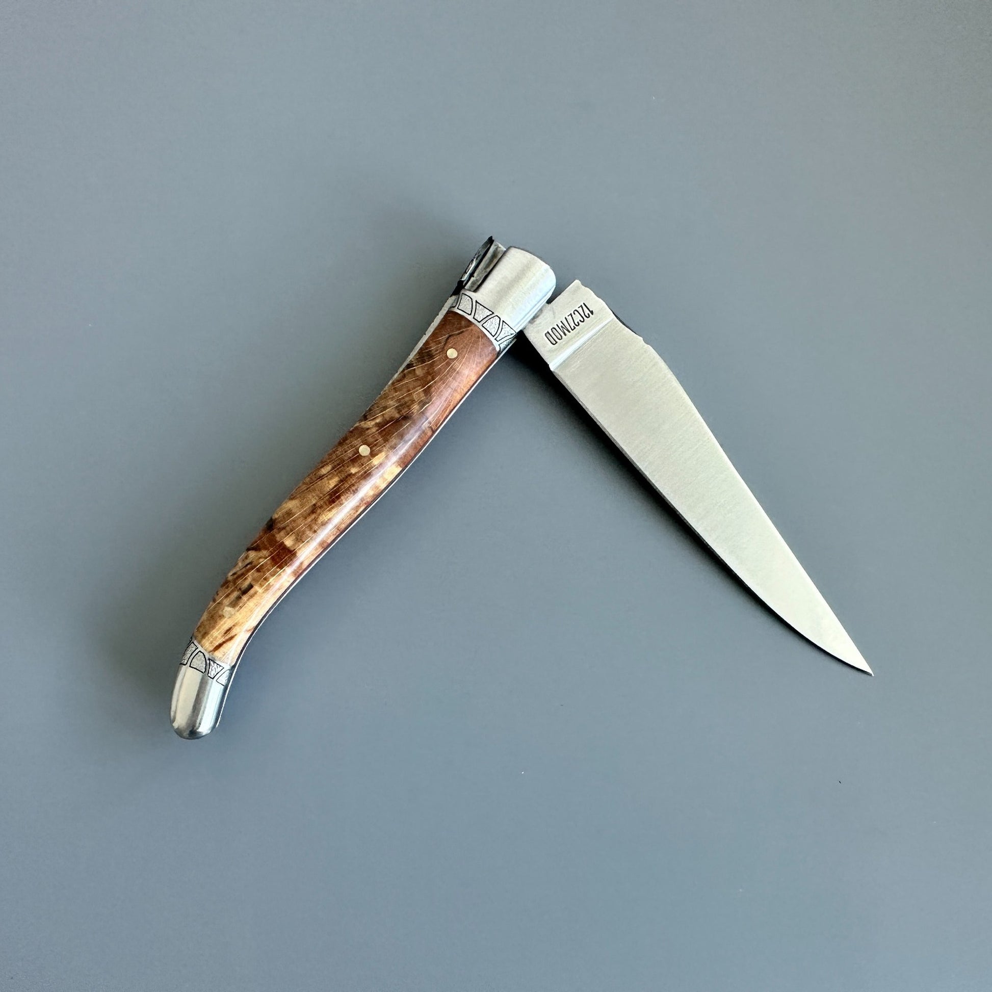 Reverse view of an open Laguiole en Aubrac Belle knife with Aubrac wood handle and red inlay