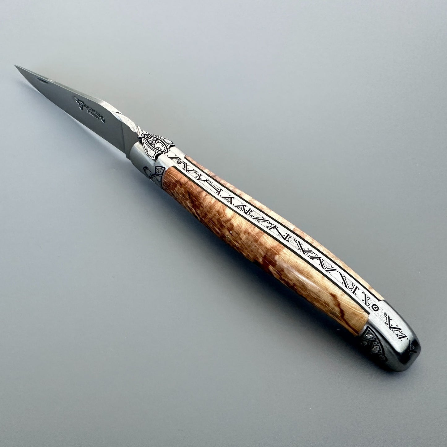 Spine view of an open Laguiole en Aubrac Belle knife showing Aubrac wood and black inlay