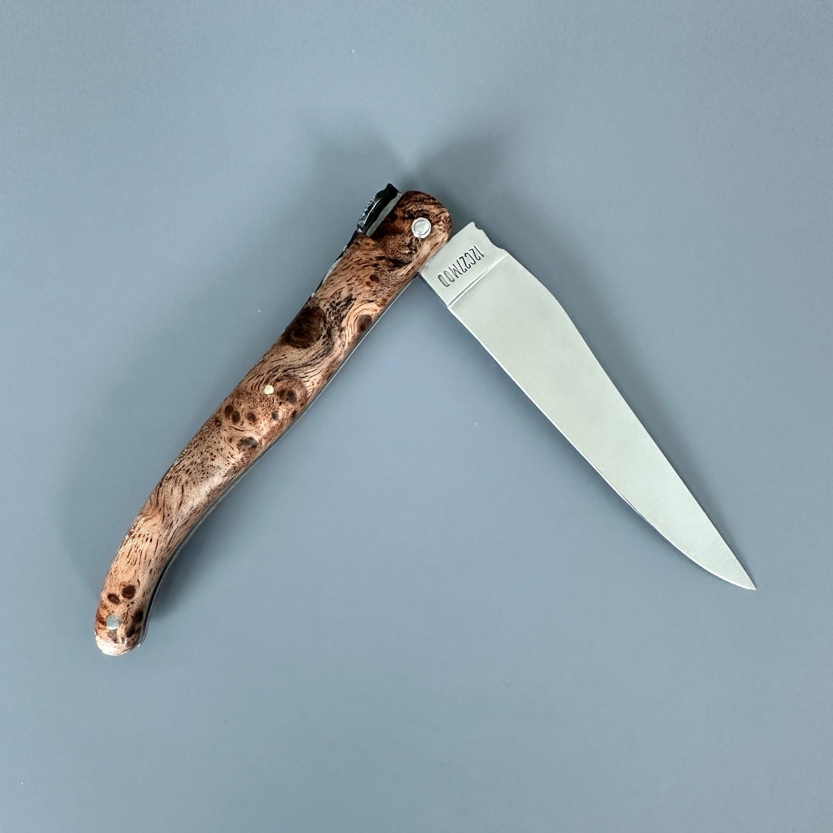 Reverse side of Laguiole en Aubrac Belle Piece partially open folding knife with Albizia handle