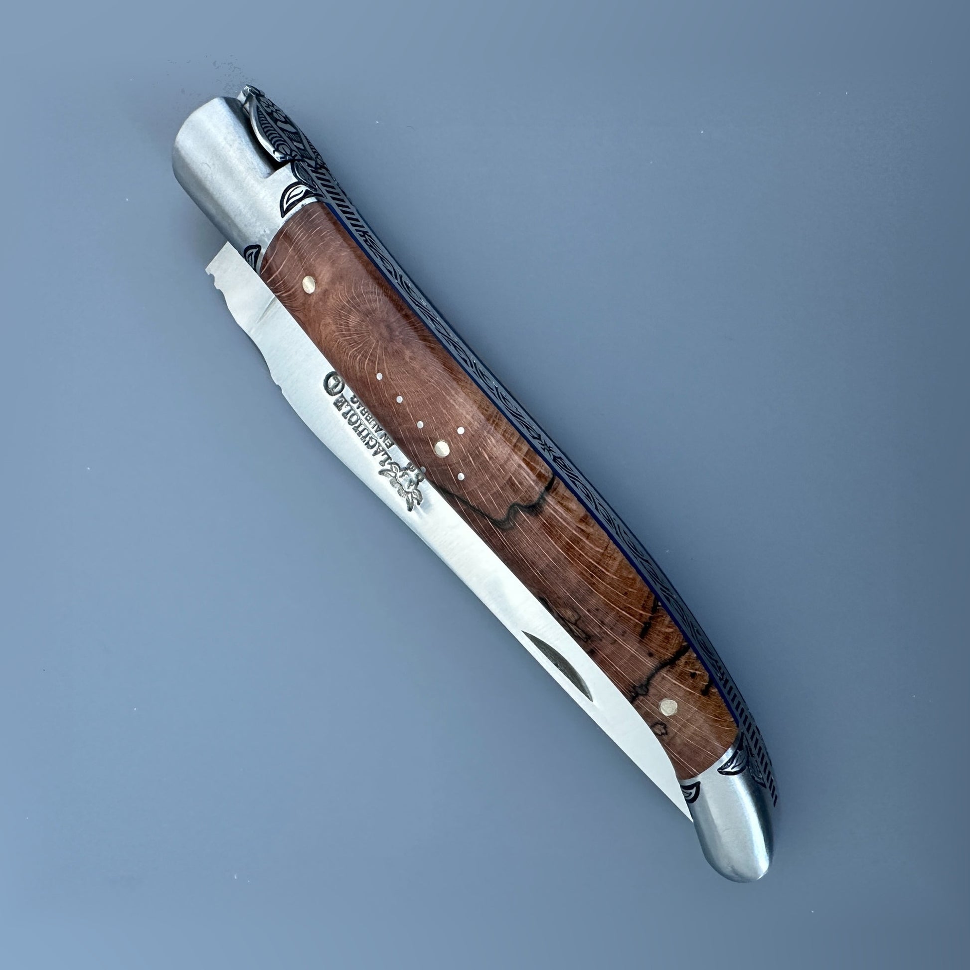 Closed front view of a Laguiole en Aubrac Belle Piece knife with wood handle, blue spacer and decorative pinwork