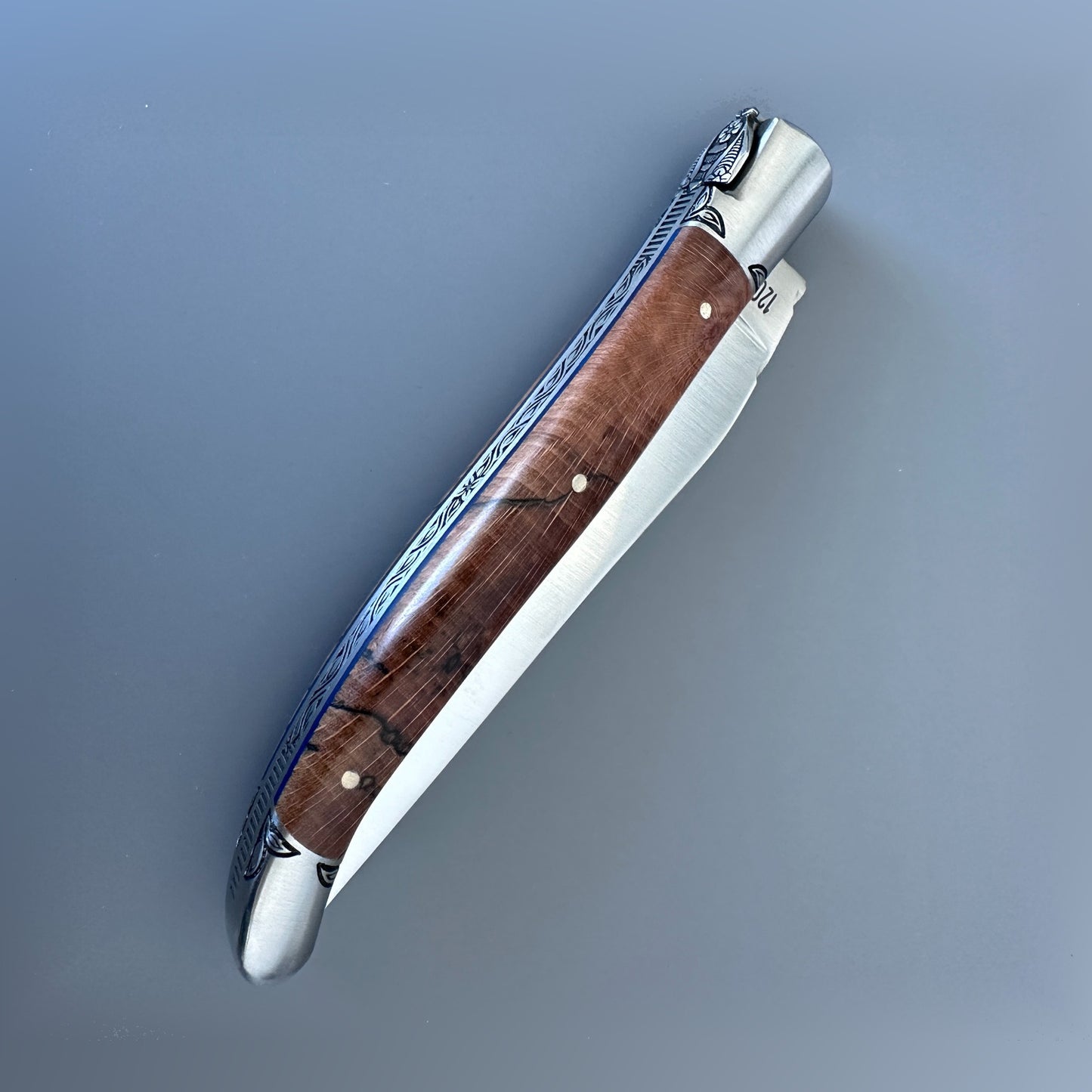 Closed reverse view of a Laguiole en Aubrac Belle Piece knife with wood handle, blue spacer and hand-filed spine