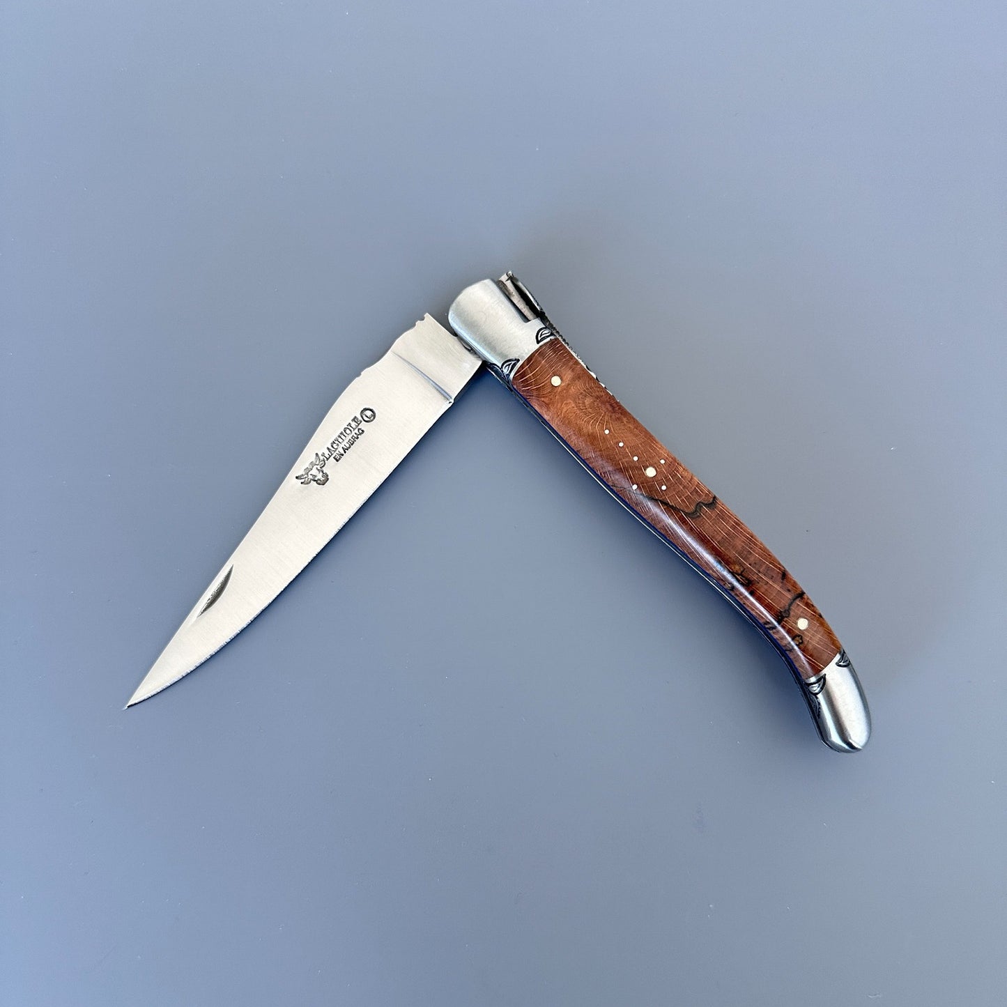 Open view of a Laguiole en Aubrac Belle Piece folding knife with wood handle and blue spacer