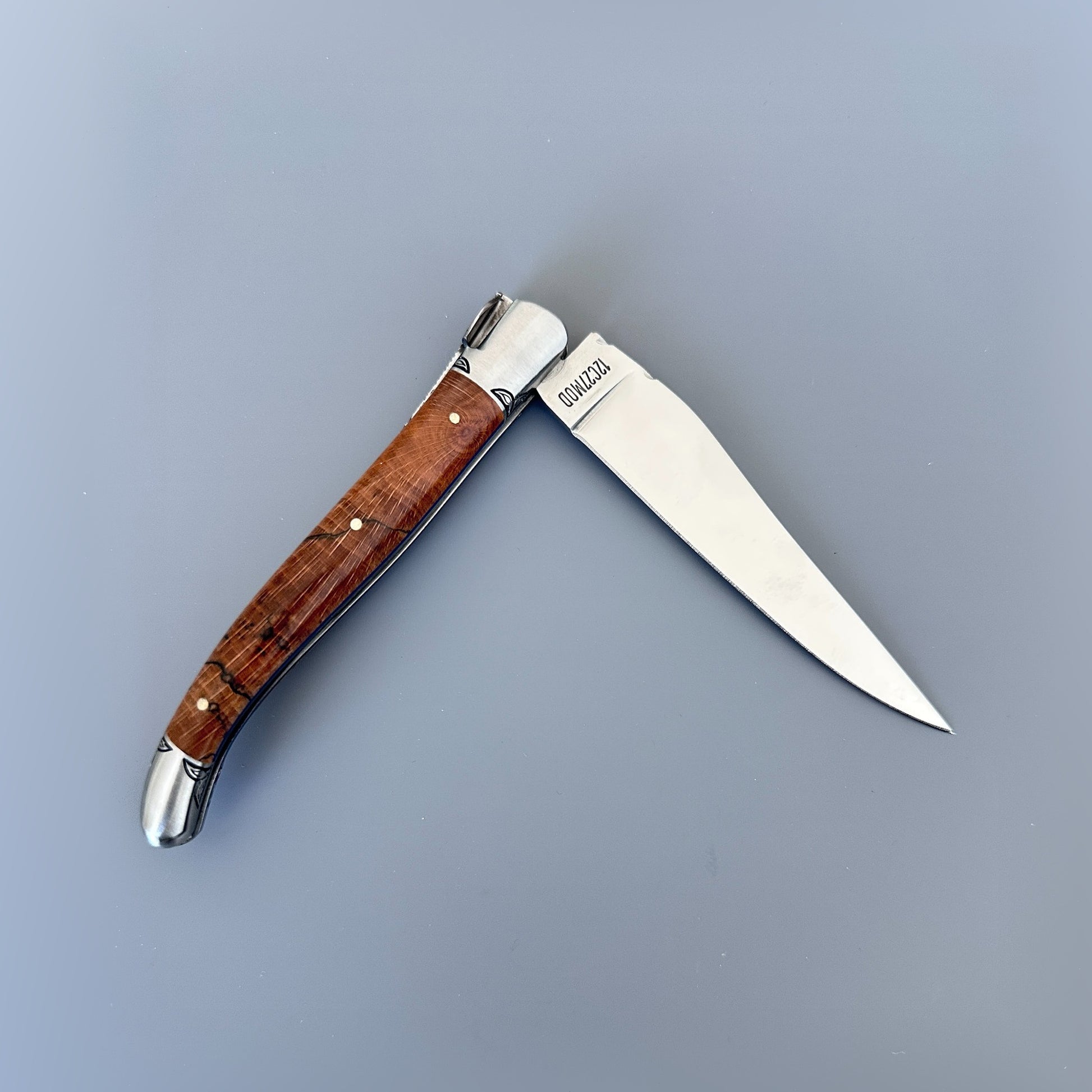 Closed reverse view of a Laguiole en Aubrac Belle Piece knife with wood handle, blue spacer and hand-filed spine