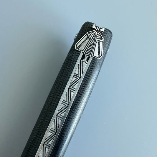 Close-up of the geometric bee ornament and engraved spine on a Laguiole en Aubrac Belle Piece Carbon folding knife.