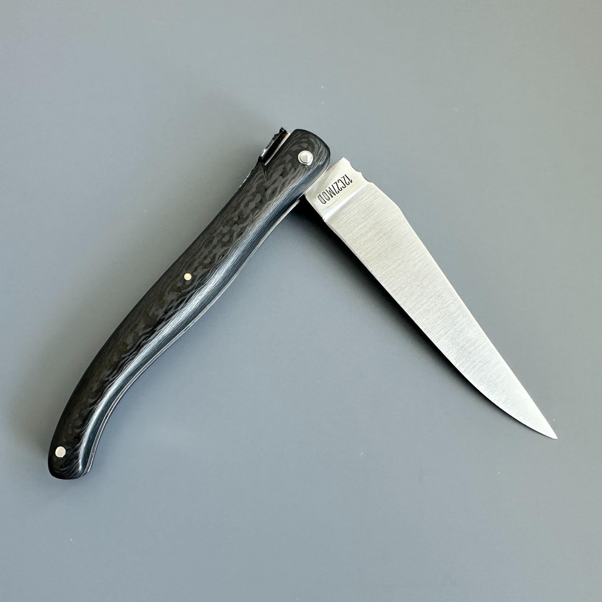 Reverse view of a partly open Laguiole en Aubrac Belle Piece Carbon folding knife with a dark carbon handle.