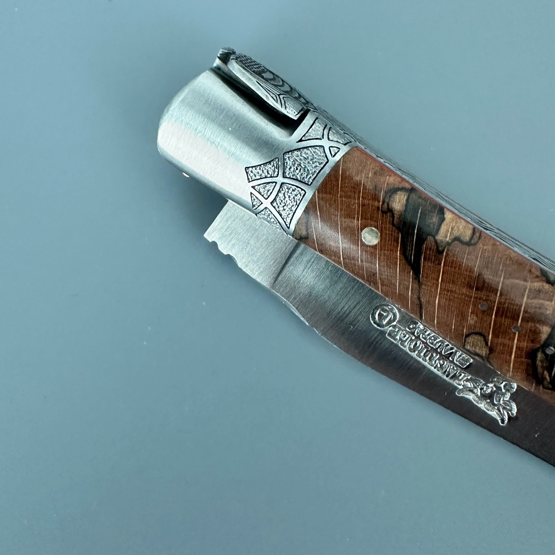 Close-up of the engraved front bolster, wood handle and Laguiole en Aubrac maker’s mark