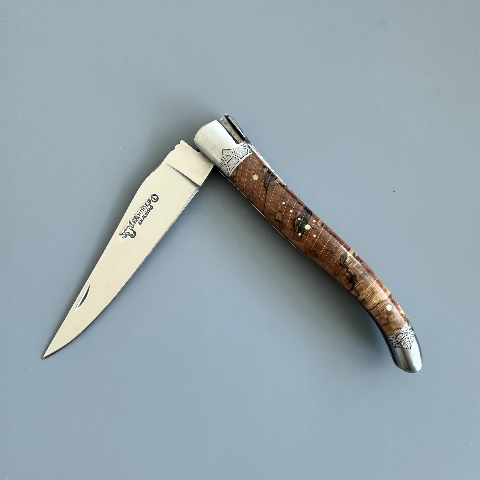 Open front view of a Laguiole en Aubrac Belle Piece folding knife with wood handle, engraved gothic bolsters
