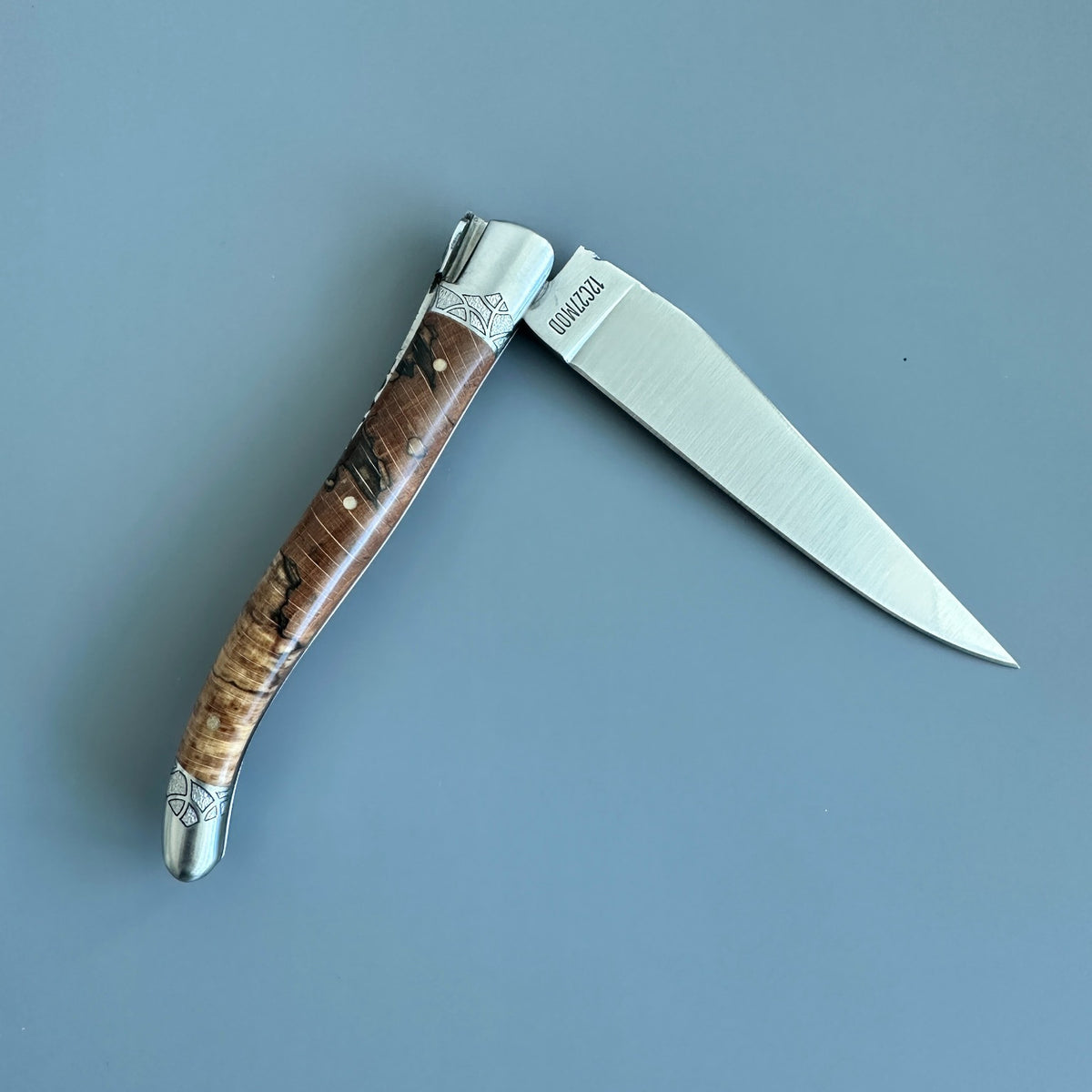 Open reverse view of a Laguiole en Aubrac Belle Piece folding knife with wood handle and engraved bolsters
