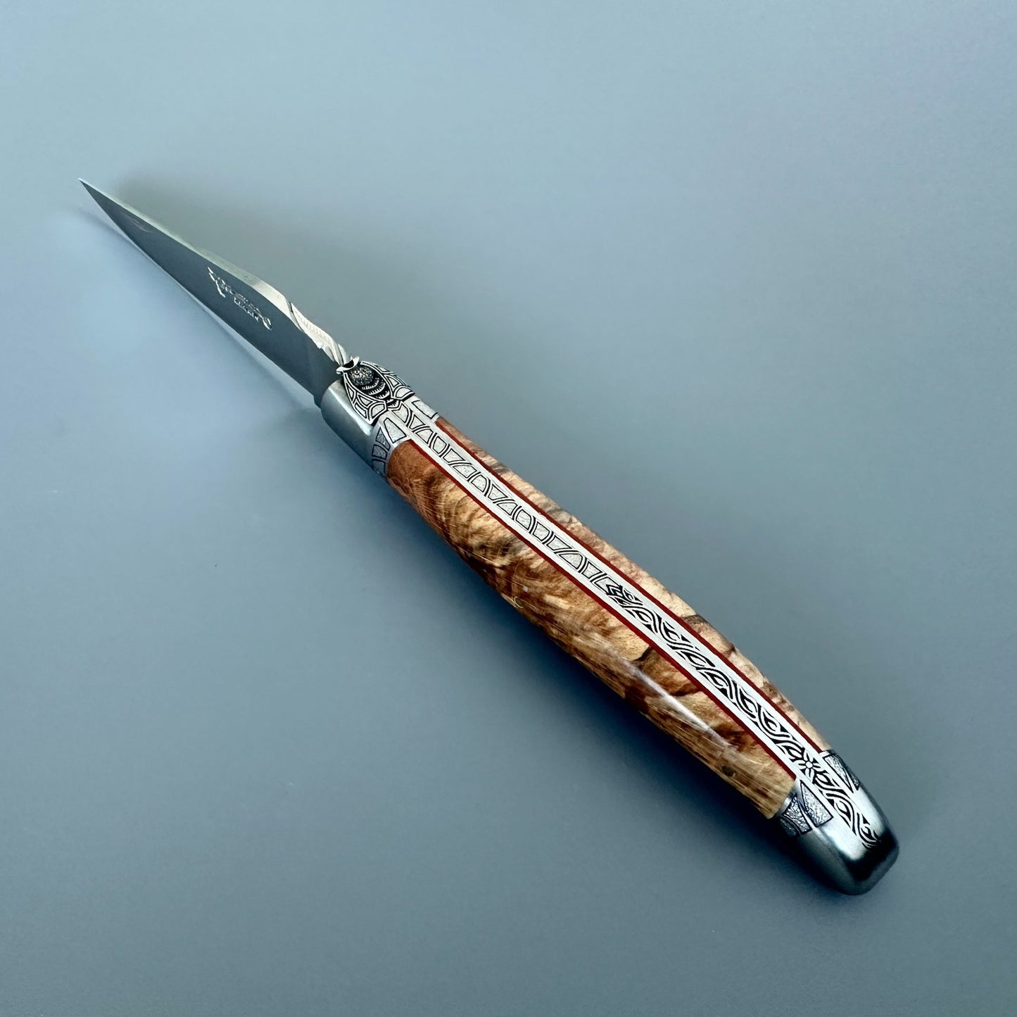Angled Laguiole en Aubrac Belle knife showing its special bee, guilloché spine and red inlay