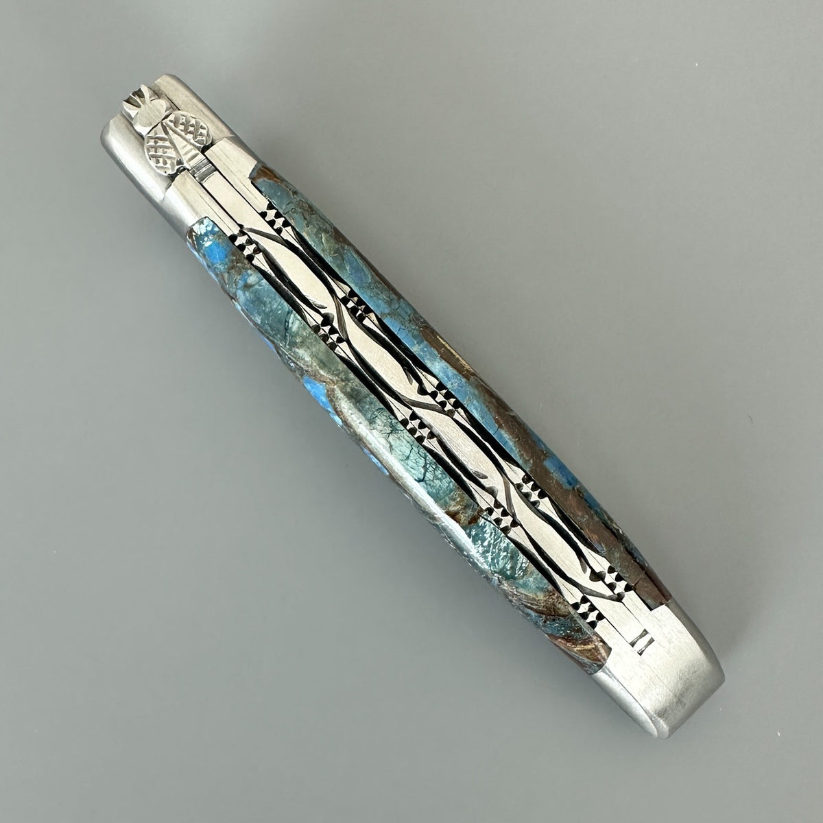 Cenital view of Laguiole en Aubrac Folding Knife with Blue Fusion handle over gray background