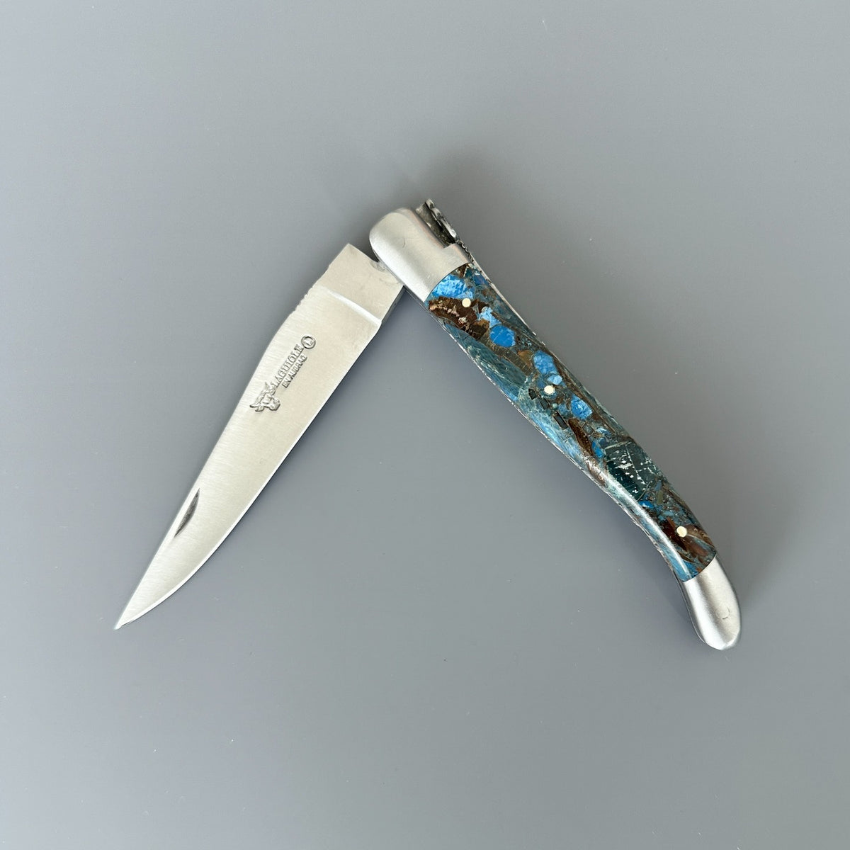 Partially open Laguiole en Aubrac Folding Knife with Blue Fusion Mammoth Ivory handle handle.