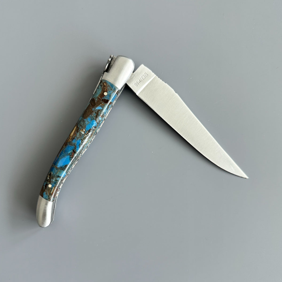 Reverse side partially open Laguiole en Aubrac Folding Knife with Blue Fusion Mammoth Ivory handle handle.